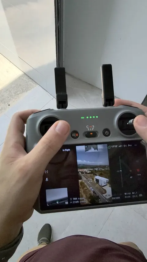 Manos sosteniendo el control del dron, con la vista aérea en vivo en la pantalla